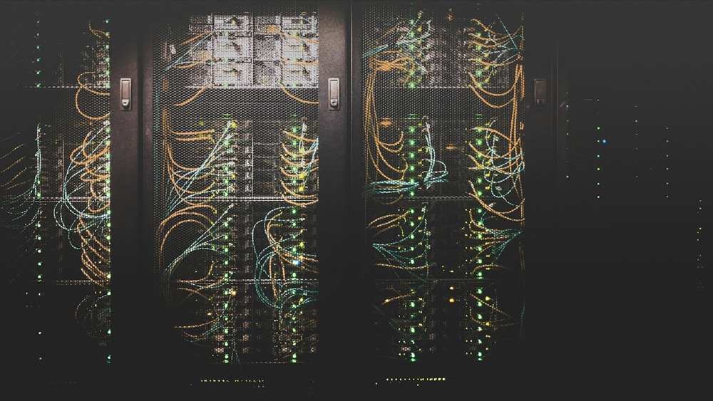 Rows of network server cabinets with illuminated cabling, representing continuous observation infrastructure