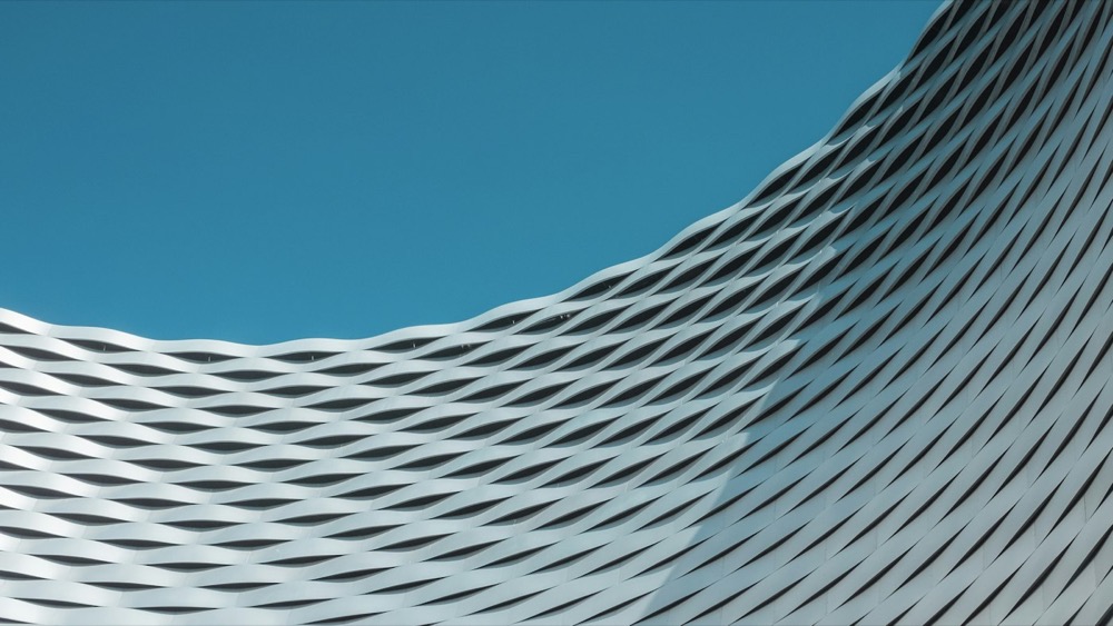 A woven architectural facade against a deep blue sky, representing a market structure that holds its shape under load